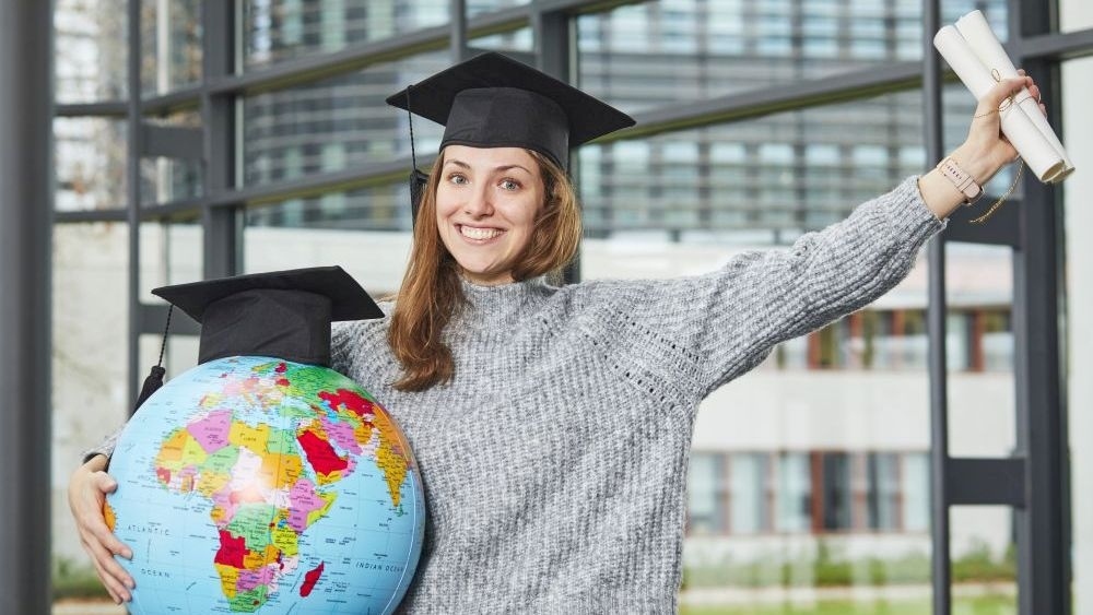 Junge Frau mit Doktorhut und Globus